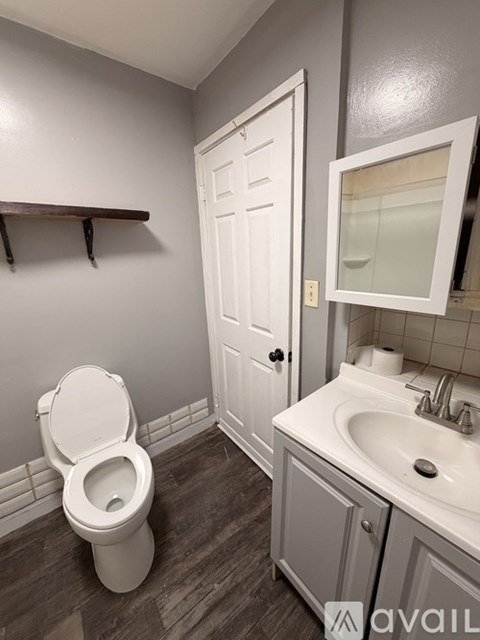 A white toilet sits in a bathroom with a white door and a white sink.