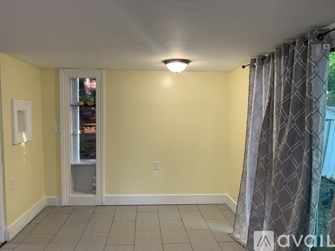 A room with yellow walls and a window with a view of trees outside.