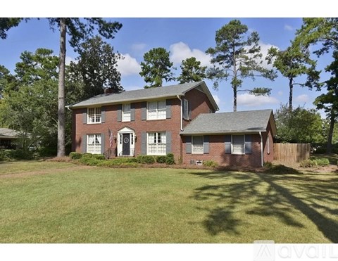 A house with a green lawn and trees in the background.