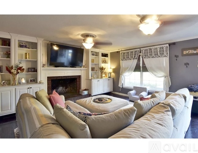 A living room with a fireplace and a television on the wall.