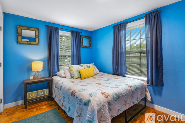 A bedroom with blue walls and a bed with a floral comforter.