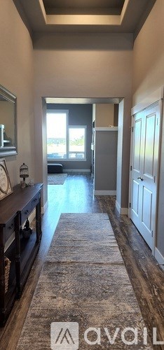 A hallway with a rug on the floor and a door on the right.
