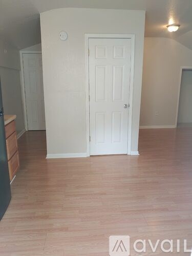 A room with a white door and wooden flooring.