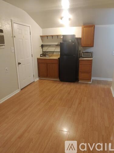 A kitchen with a black fridge and wooden floors.