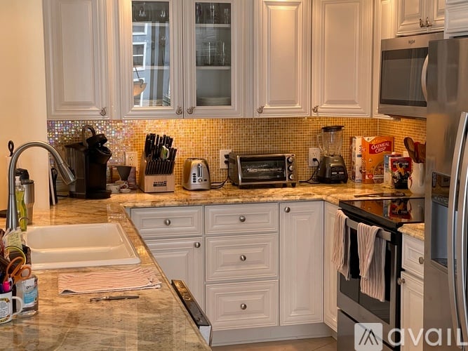 A kitchen with white cabinets and a tiled backsplash.