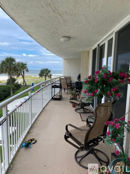 A balcony with chairs and a table with flowers.