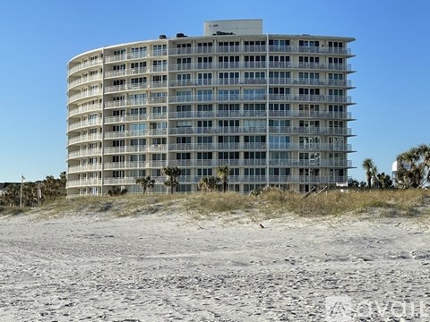 A large building with many windows sits on a sandy beach.