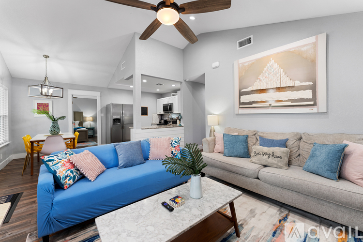 A living room with a blue couch and a ceiling fan.