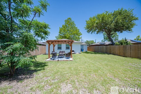 A backyard with a gazebo and a tree.