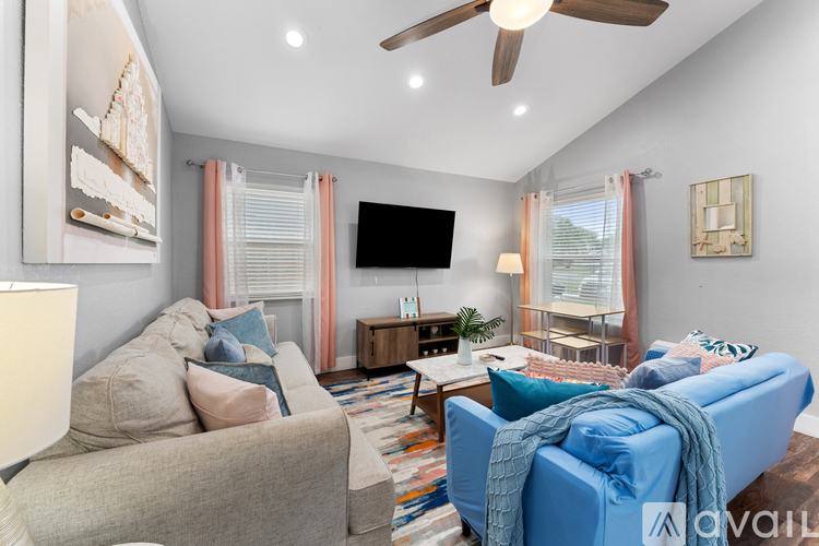 A living room with a blue couch and a television on the wall.