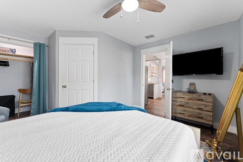 A bedroom with a large bed and a flat screen TV mounted on the wall.