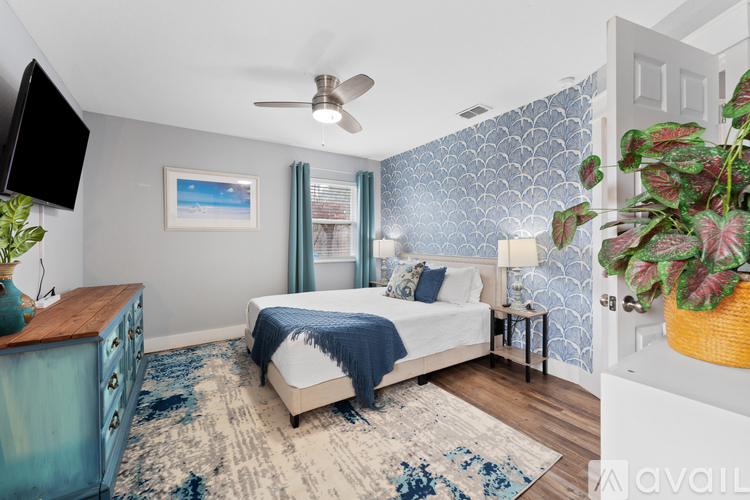 A bedroom with a bed, a dresser, and a ceiling fan.
