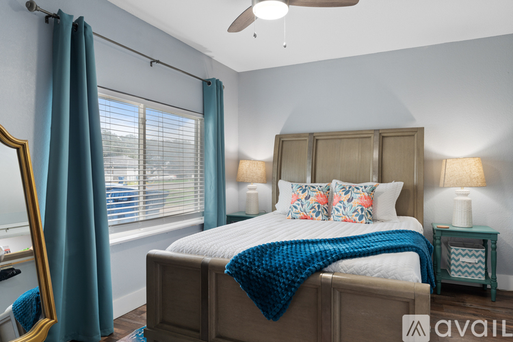 A bedroom with a bed, a ceiling fan, and a window with blue curtains.