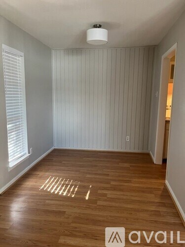 A room with wooden flooring and a window with blinds.