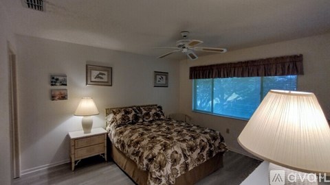 A bedroom with a bed, nightstand, and window.