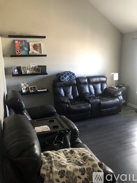 A living room with black leather furniture and pictures on the wall.