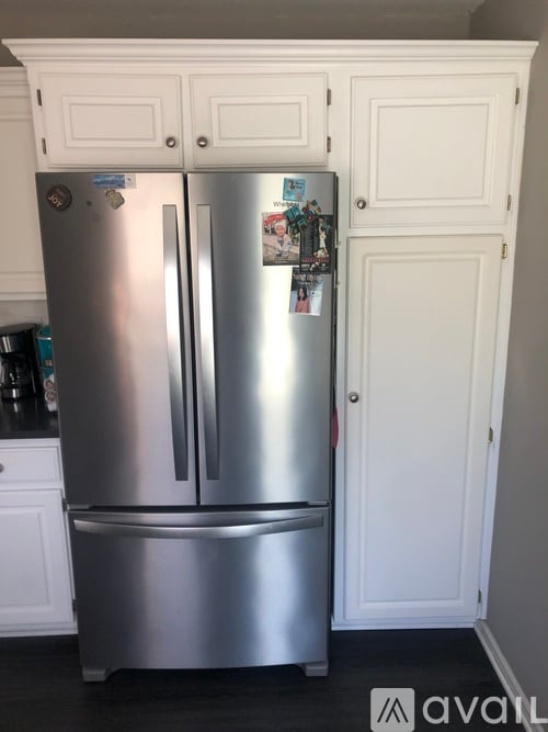 A silver fridge with a white door and a white cabinet with a white door.