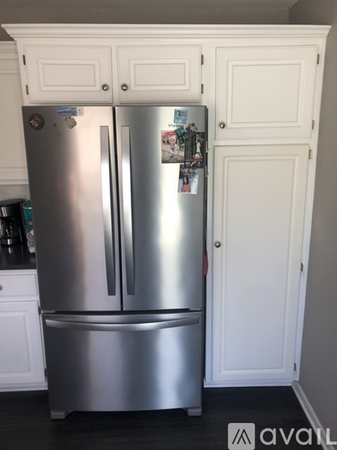A silver fridge with a white door and a white cabinet with a white door.