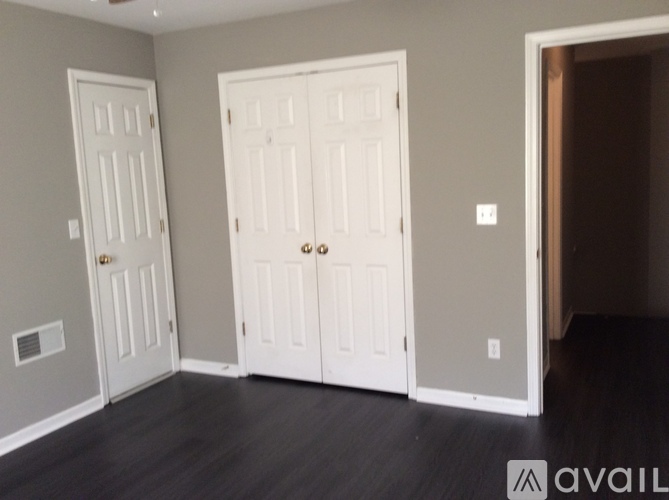 A room with two white doors and a grey wall.