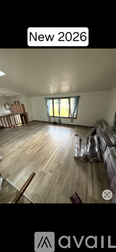 A room with wooden flooring and a window with sunlight coming through.