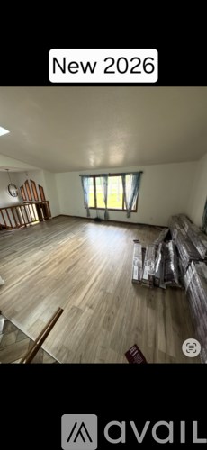 A room with wooden flooring and a window with sunlight coming through.