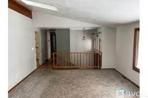 A room with a carpeted floor and a wooden gate.