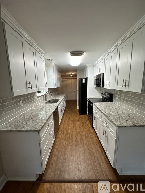 A kitchen with white cabinets and a wooden floor.