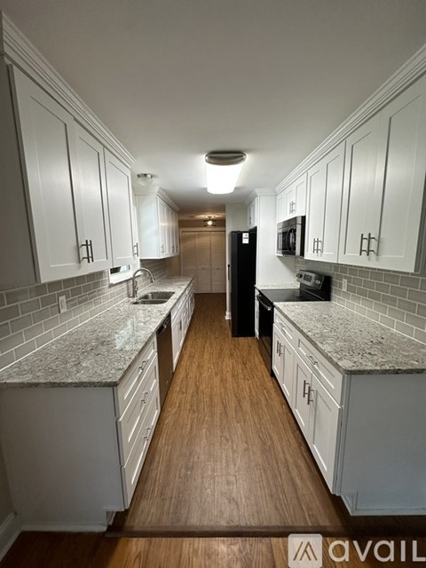 A kitchen with white cabinets and a wooden floor.