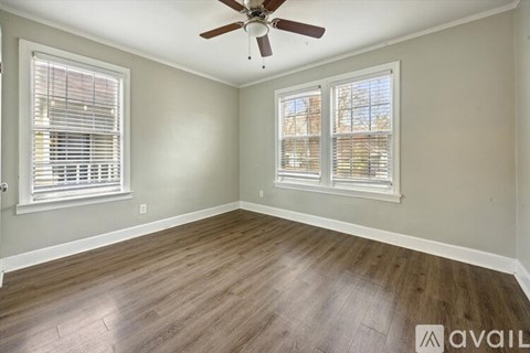 A room with a ceiling fan and two windows with blinds.
