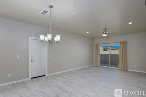 A spacious room with a chandelier, a door, and a window with curtains.
