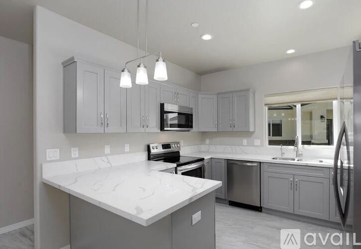 A modern kitchen with a white marble countertop and grey cabinets.