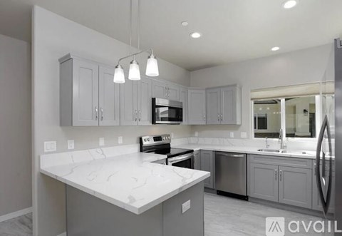 A modern kitchen with a white marble countertop and grey cabinets.