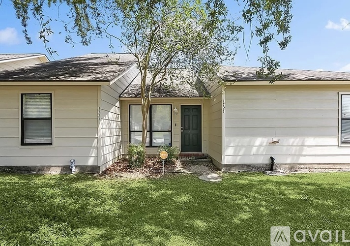 A house with a green door and a tree in front.