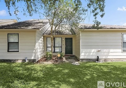A house with a green door and a tree in front.