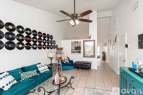 A living room with a green couch and a wall of records.
