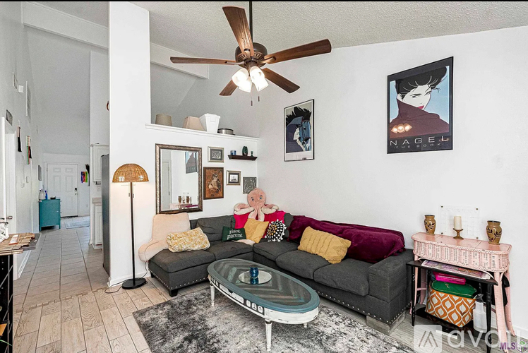 A living room with a grey couch and a ceiling fan.