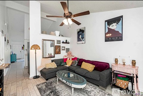 A living room with a grey couch and a ceiling fan.