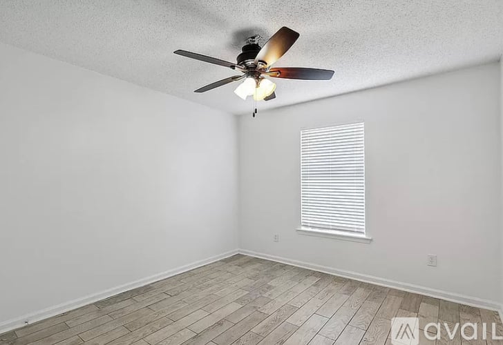A room with a ceiling fan and a window with blinds.