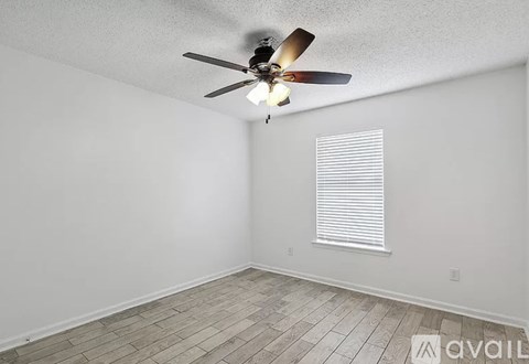 A room with a ceiling fan and a window with blinds.
