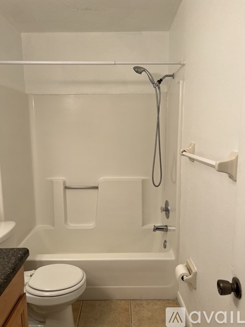 A white bathroom with a toilet, tub, and towel rack.