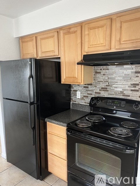 A black fridge and stove in a kitchen with wooden cabinets.