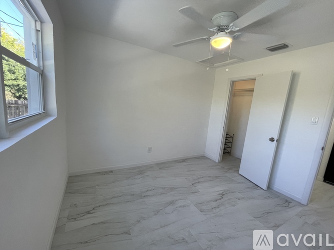 A room with a ceiling fan and a marble floor.