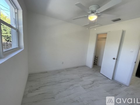A room with a ceiling fan and a marble floor.