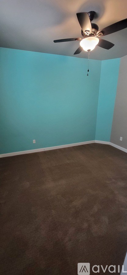 A room with a ceiling fan and a brown floor.
