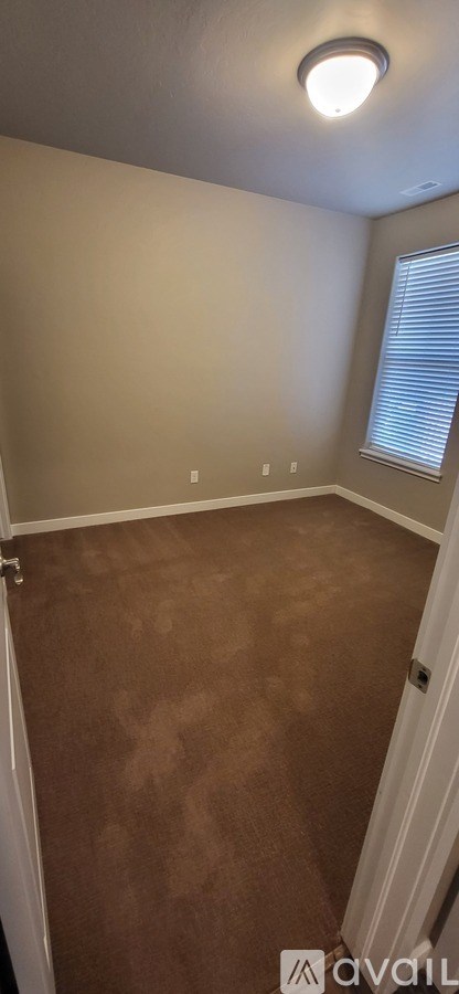 A room with a carpeted floor and a window with blinds.