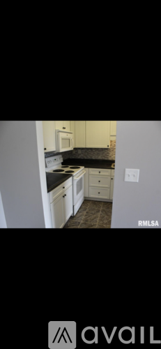 A kitchen with white cabinets and a black countertop.