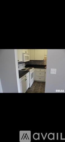 A kitchen with white cabinets and a black countertop.