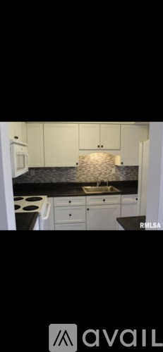 A kitchen with white cabinets and a black countertop.