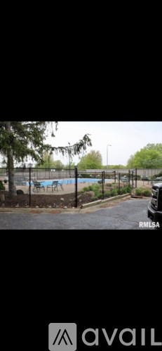 A pool surrounded by a fence with trees in the background.