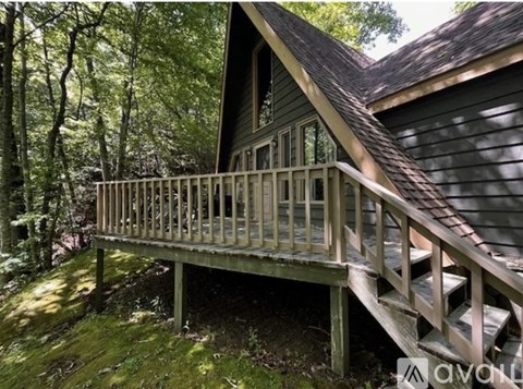 A wooden deck leads up to a house in a wooded area.